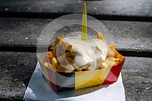 Paper box in colors of Belgian flag with fried potato frit chips and mayonnaise sauÑe
