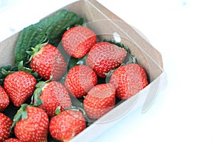 Paper box with red strawberry for sale in the fruit and vegetable market. Close up. Tasty seasonal fruit, fresh and heathy.