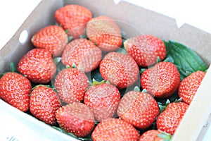 Paper box with red strawberry for sale in the fruit and vegetable market. Close up. Tasty seasonal fruit, fresh and heathy.