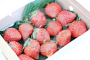 Paper box with red strawberry for sale in the fruit and vegetable market. Close up. Tasty seasonal fruit, fresh and heathy.