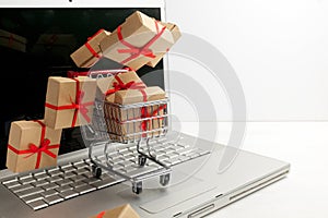 Paper boxes in a shopping cart on a laptop keyboard. Ideas about e-commerce, a transaction of buying or selling goods or