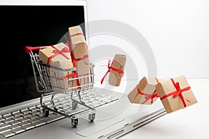 Paper boxes in a shopping cart on a laptop keyboard. Ideas about e-commerce, a transaction of buying or selling goods or