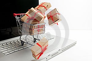 Paper boxes in a shopping cart on a laptop keyboard. Ideas about e-commerce, a transaction of buying or selling goods or