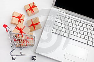 Paper boxes in a shopping cart on a laptop keyboard. Ideas about e-commerce, a transaction of buying or selling goods or