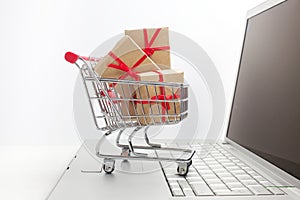 Paper boxes in a shopping cart on a laptop keyboard. Ideas about e-commerce, a transaction of buying or selling goods or