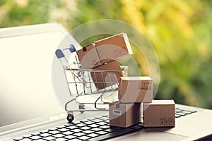 Paper boxes in a shopping cart on notebook keyboard. Ideas about e-commerce or electronic commerce is a transaction of buying or
