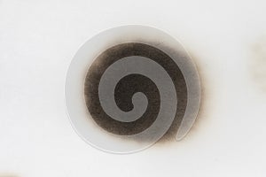 Paper burn black  stain isolated over the white background. Round paper burn mark close up