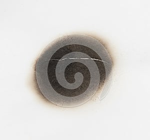 Paper burn black  stain isolated over the white background. Round paper burn mark close up