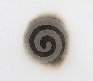 Paper burn black  stain isolated over the white background. Round paper burn mark close up