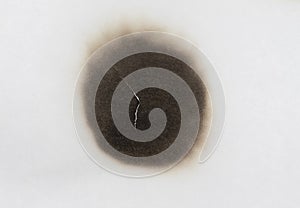 Paper burn black  stain isolated over the white background. Round paper burn mark close up