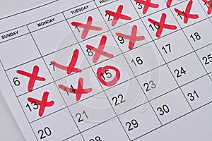 Paper calendar with red crosses and circle closeup-up.