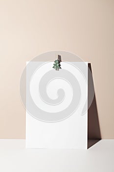 paper card note with paper clip in form of Christmas tree on beige background.