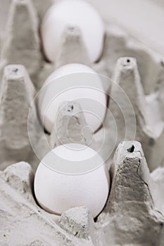 Paper cardboard box egg tray lies on table with demanding white eggs.