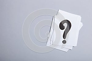 Paper cards with question marks on grey background. Pile of question marks, top view with place for text