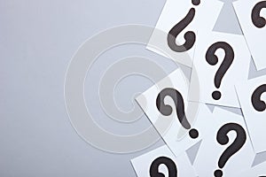 Paper cards with question marks on grey background. Pile of question marks, top view with place for text