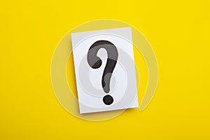 Paper cards with question marks on yellow background. Pile of question marks, top view