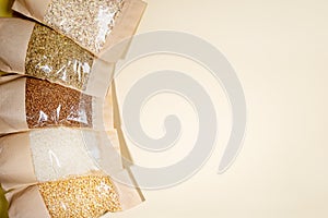 Paper-cellophane bags of cereals, legumes close-up on beige. Copy space. Stock for a rainy day. Stock for quarantine