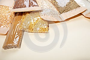 Paper-cellophane bags with cereals, legumes and pasta on beige. Quarantine stock. Copy space