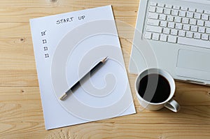 Paper check list for start up business laptop and coffee.