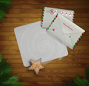 Paper Christmas invitation and two mail envelopes on the wooden background with christmas tree,