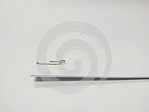 Paper clip holding a blank paper sheet on white background.