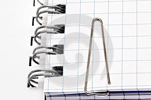 Paper clip on notebook pages. Isolated over white.