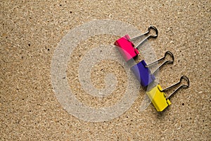 Paper clip. Three colored clothespins on a chipboard