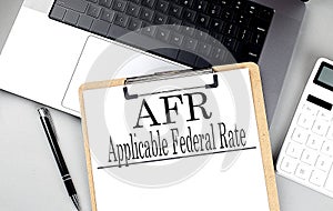 Paper clipboard with AFR on laptop with pen and calculator photo