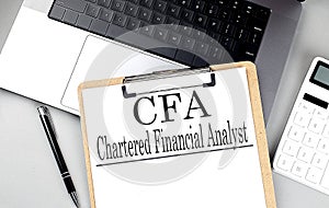 Paper clipboard with CFA on laptop with pen and calculator