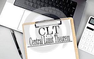 Paper clipboard with CLT on laptop with pen and calculator