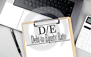 Paper clipboard with Debt to equity ratio on laptop with pen and calculator