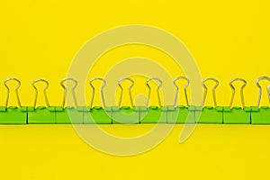 Paper clips, pins and binders on yellow background