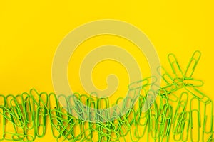 Paper clips, pins and binders on yellow background