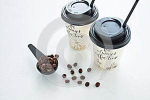 Paper coffee cup from coffee shop with coffee beans near the window. Lifestyle concept