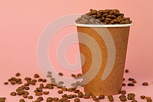 Paper coffee cup full of coffee beans on pink background. Copy space.