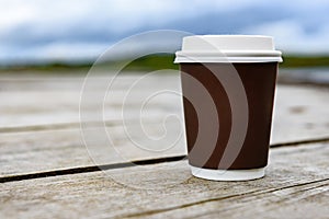 Paper coffee cup by a lake.