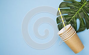 Paper coffee cups made of natural eco-friendly material, on tropical leaves on a blue background