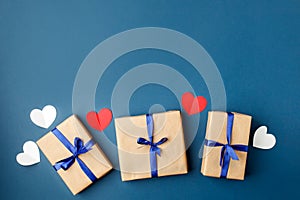 Paper craft gift boxes with bow on blue background with hearts, copy space. Greeting card concept. Saint Valentine, romance, Dad