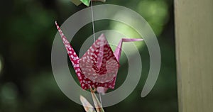 A paper crane swaying in the wind at the traditional street close up handheld