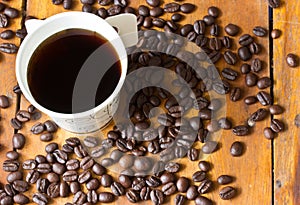 A paper cup of black coffee and coffee beans on table