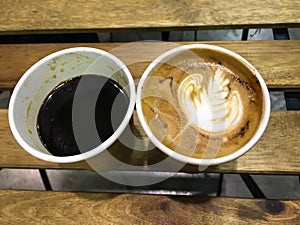 Paper cup of cappuccino coffee and Paper cup of americano coffee on wooden table background, Close up, Slow life cafe concept