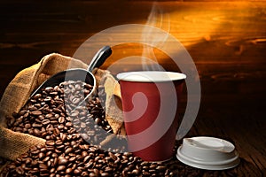 Paper cup of coffee with smoke and coffee beans on old wooden