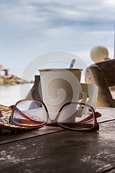 Paper Cup of Coffee on wood table in the seaside