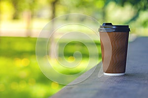 A paper cup of coffee on a wooden bar counter.