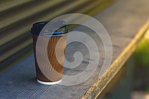 A paper cup of coffee on a wooden bar counter.