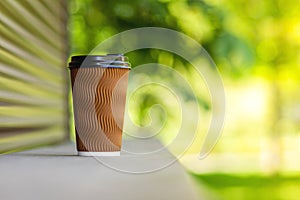 A paper cup of coffee on a wooden bar counter.