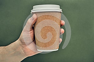 Paper cup in hand on a colored background. Eco-friendly materials in a coffee shop, biodegradable disposable tableware