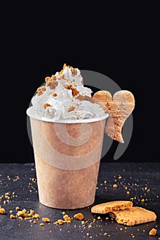 Paper cup with hot drink with whipped cream on dark background. Recycling and eco friendly concept.