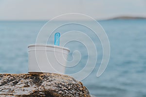 Paper cup for ice cream on the stone beach with sea background