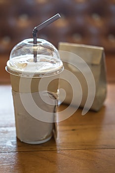 Paper cup of iced coffee on wooden table